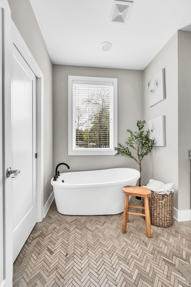 bathroom featuring parquet flooring and a bathtub