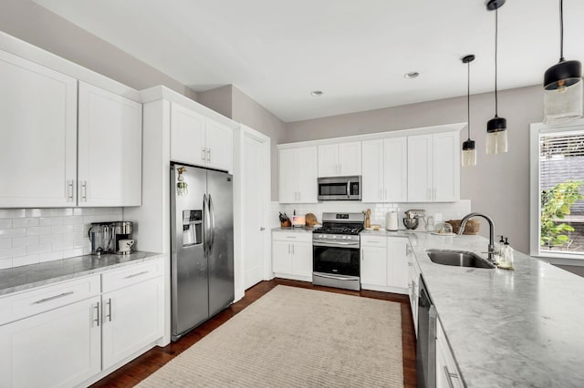 kitchen with sink, white cabinetry, tasteful backsplash, decorative light fixtures, and appliances with stainless steel finishes