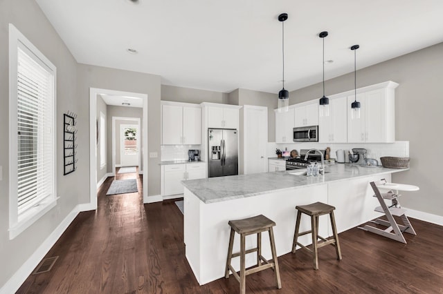 kitchen with pendant lighting, appliances with stainless steel finishes, kitchen peninsula, and white cabinets