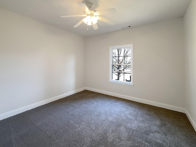 spare room featuring ceiling fan and dark carpet