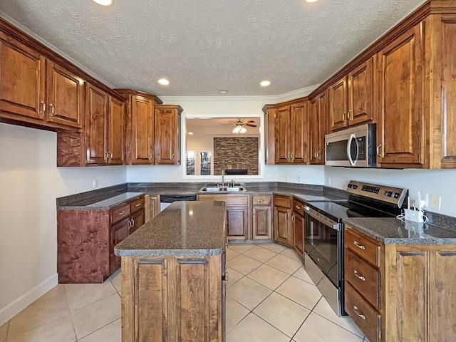 kitchen with sink, light tile patterned floors, ceiling fan, appliances with stainless steel finishes, and a kitchen island