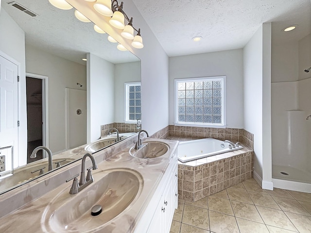 bathroom with independent shower and bath, vanity, tile patterned floors, and a textured ceiling