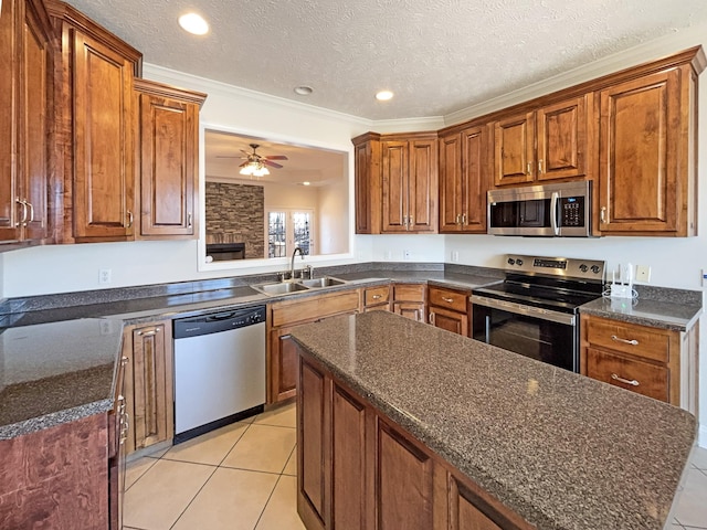 kitchen featuring sink, stainless steel appliances, a center island, a textured ceiling, and light tile patterned flooring