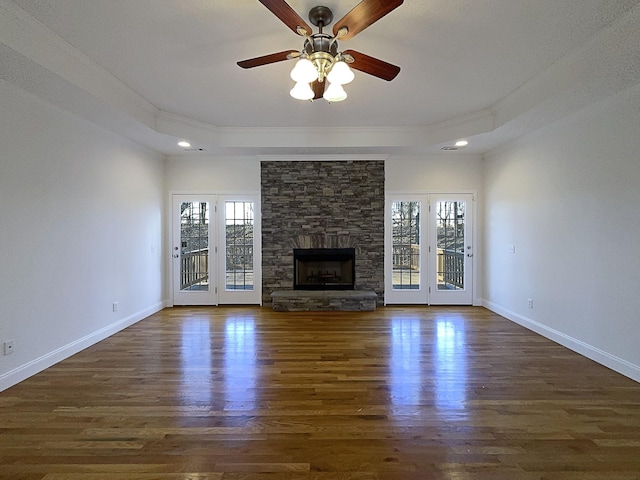 unfurnished living room with a healthy amount of sunlight, a fireplace, and a tray ceiling