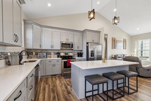 kitchen with dark hardwood / wood-style floors, decorative light fixtures, sink, a kitchen breakfast bar, and stainless steel appliances