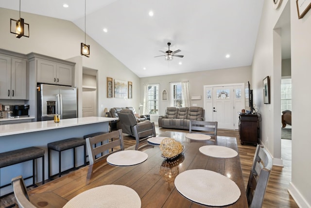 dining room with ceiling fan, dark hardwood / wood-style flooring, and high vaulted ceiling