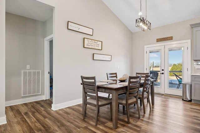 dining space with lofted ceiling, a chandelier, dark hardwood / wood-style flooring, and french doors