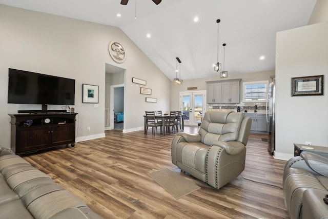 living room with hardwood / wood-style flooring, ceiling fan, sink, and high vaulted ceiling