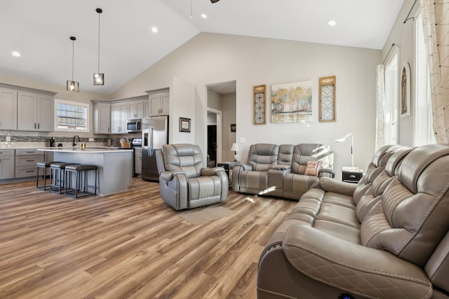 living room featuring high vaulted ceiling and light wood-type flooring