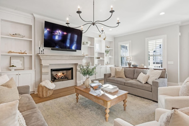 living room featuring crown molding, built in features, a fireplace, and light hardwood / wood-style flooring