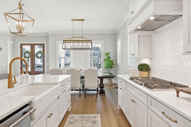 kitchen featuring pendant lighting, white cabinetry, custom exhaust hood, and appliances with stainless steel finishes