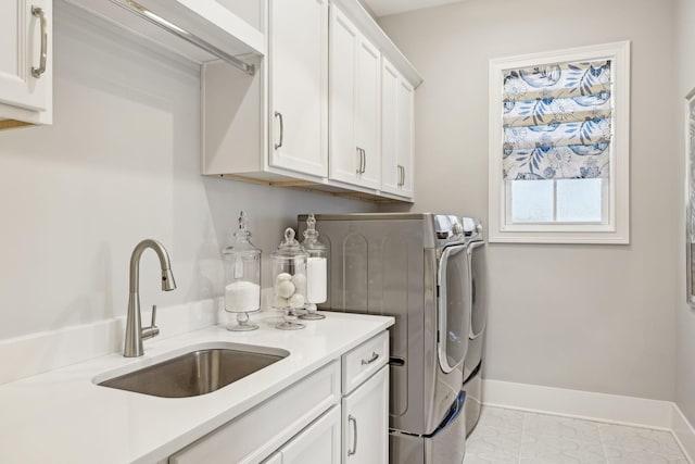 clothes washing area with cabinets, sink, and washer and dryer