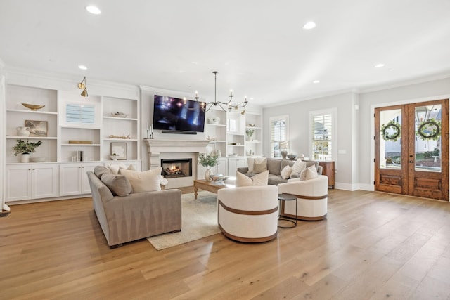 living room with crown molding, a notable chandelier, light wood-type flooring, and french doors