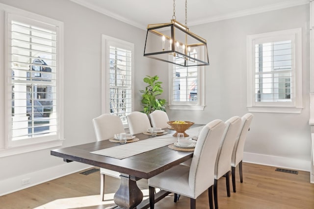 dining space featuring hardwood / wood-style flooring, ornamental molding, and a chandelier