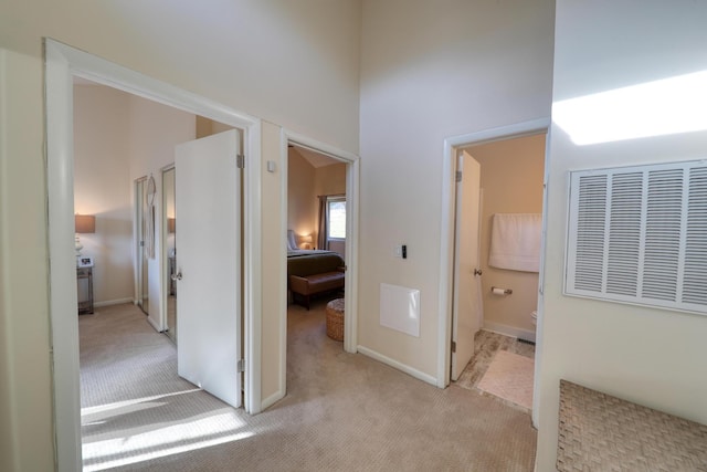 corridor with light carpet and a towering ceiling