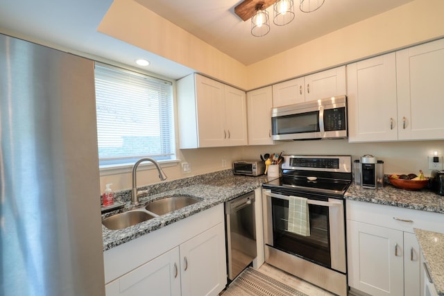 kitchen featuring appliances with stainless steel finishes, stone countertops, sink, and white cabinets