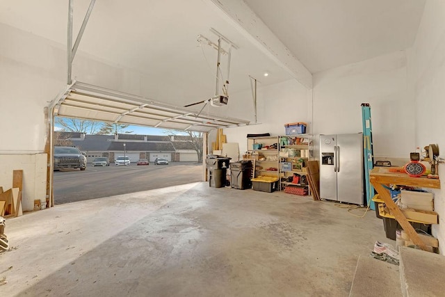 garage with a garage door opener and stainless steel fridge