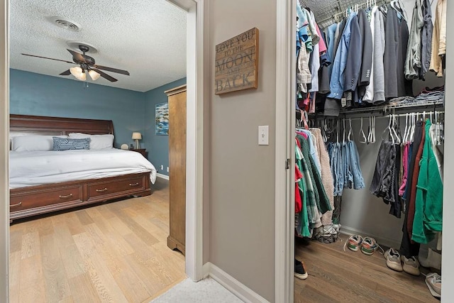 bedroom with ceiling fan, a textured ceiling, and light hardwood / wood-style flooring