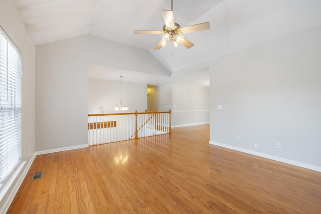 unfurnished room featuring hardwood / wood-style flooring, lofted ceiling, and ceiling fan with notable chandelier