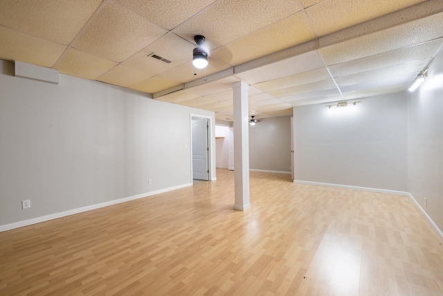 basement featuring ceiling fan, wood-type flooring, and a drop ceiling