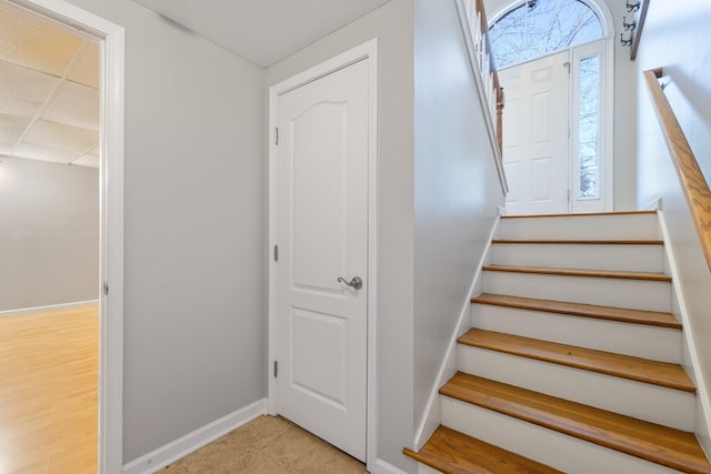 stairs with a paneled ceiling