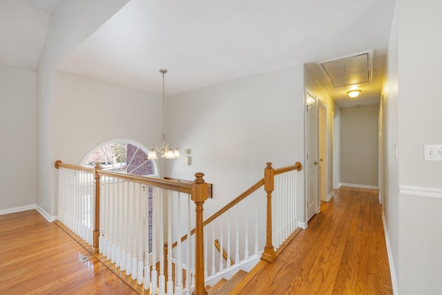 hallway featuring an inviting chandelier and light hardwood / wood-style floors