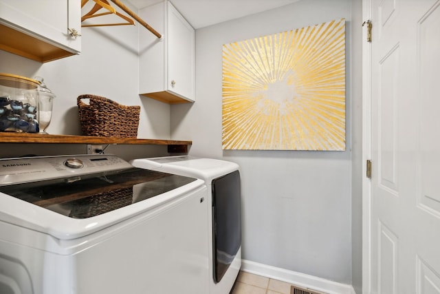 washroom featuring cabinets, washer and dryer, and light tile patterned floors