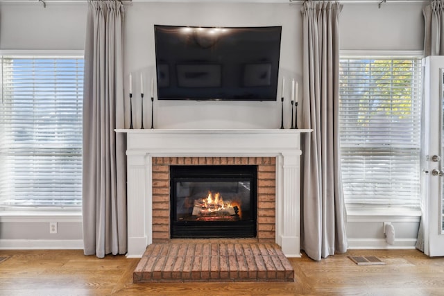 interior details featuring wood-type flooring and a brick fireplace