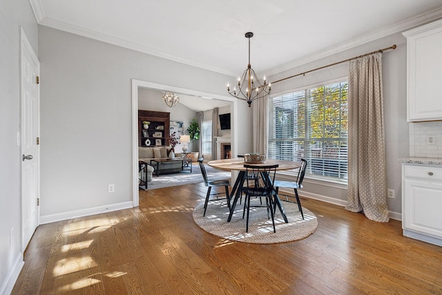 dining room with ornamental molding, wood-type flooring, and a chandelier