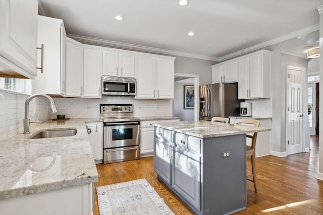 kitchen featuring white cabinetry, sink, stainless steel appliances, and a kitchen island