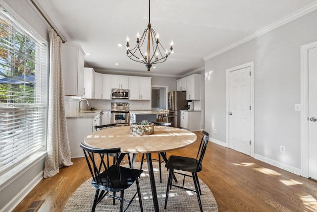 dining space featuring crown molding, sink, hardwood / wood-style floors, and a chandelier