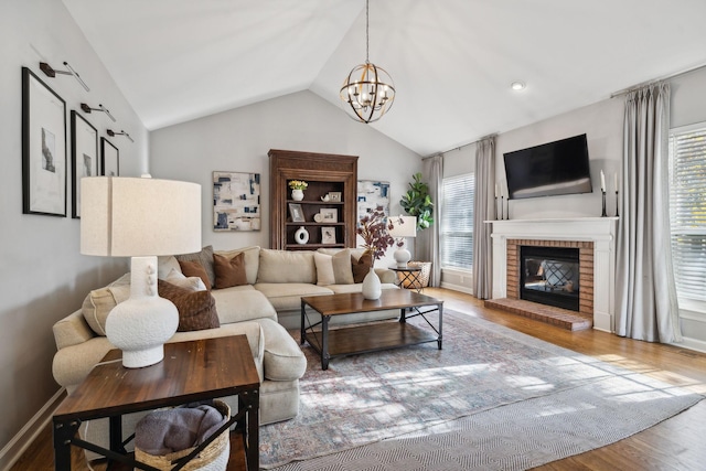 living room featuring hardwood / wood-style flooring, vaulted ceiling, plenty of natural light, and a fireplace