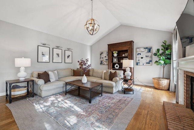 living room with hardwood / wood-style floors, a fireplace, a chandelier, and vaulted ceiling