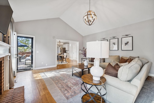 living room with a notable chandelier, light hardwood / wood-style flooring, and high vaulted ceiling