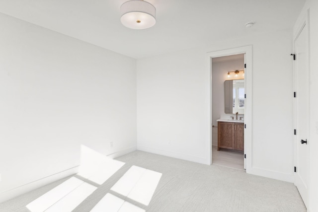 spare room featuring sink and light colored carpet