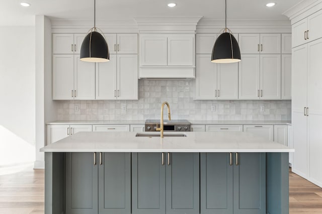 kitchen featuring light stone counters, pendant lighting, and an island with sink