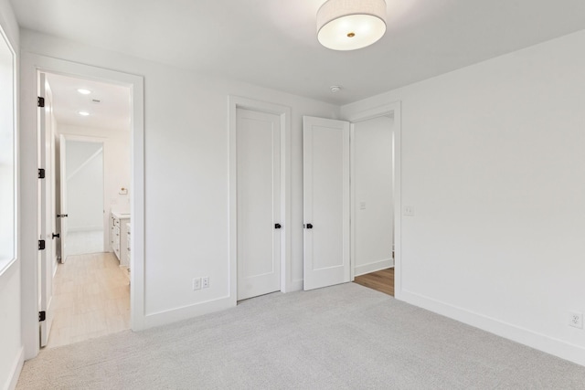 unfurnished bedroom with light colored carpet and a closet