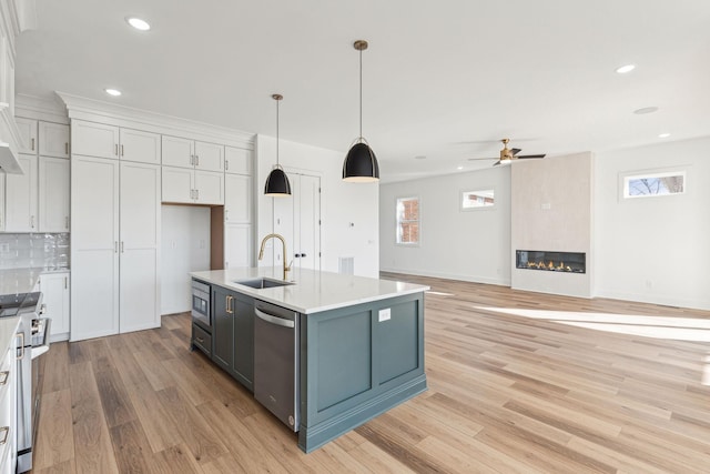 kitchen featuring decorative light fixtures, sink, white cabinets, a kitchen island with sink, and stainless steel appliances