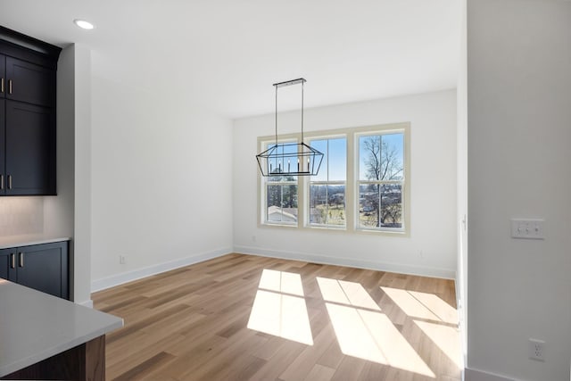 unfurnished dining area with a chandelier and light hardwood / wood-style flooring