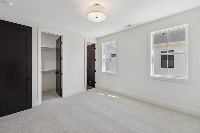 unfurnished bedroom featuring a spacious closet and light colored carpet