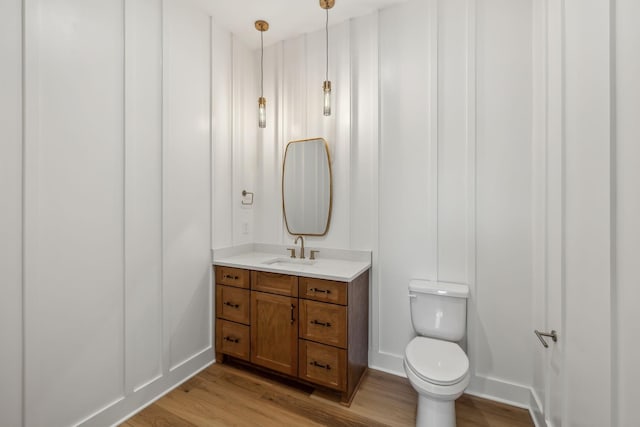 bathroom with hardwood / wood-style flooring, vanity, and toilet