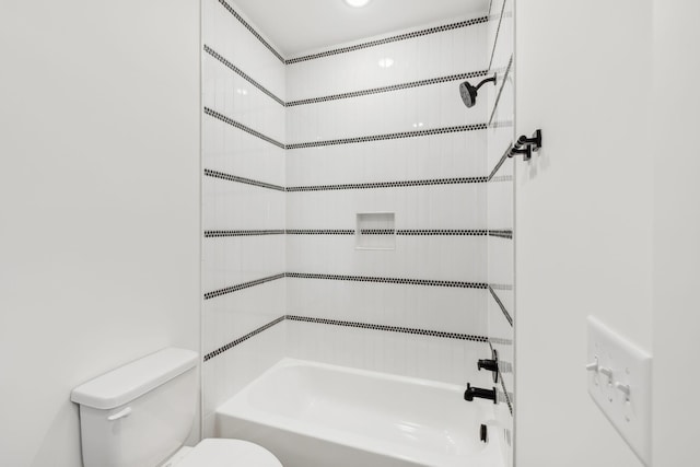 bathroom featuring tiled shower / bath combo and toilet