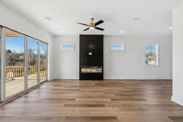 unfurnished living room featuring hardwood / wood-style flooring, a large fireplace, and ceiling fan