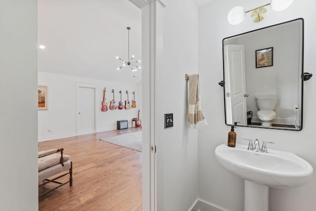 bathroom with sink, wood-type flooring, a chandelier, and toilet