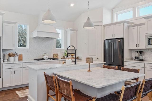 kitchen with a kitchen island with sink, hanging light fixtures, a kitchen breakfast bar, and appliances with stainless steel finishes