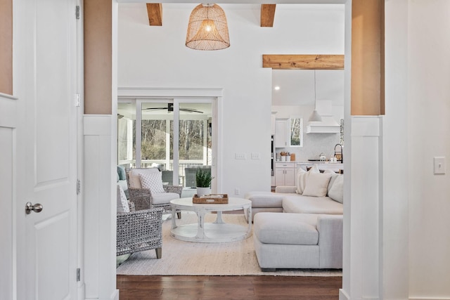 living room featuring ceiling fan, dark wood-type flooring, sink, and beam ceiling