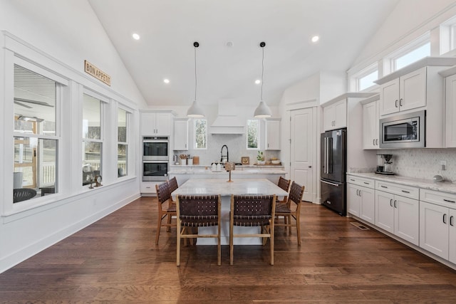 kitchen featuring pendant lighting, stainless steel appliances, light stone countertops, and a kitchen island