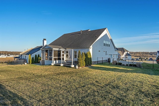 rear view of house with a lawn and a sunroom