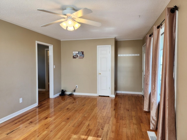 interior space with ceiling fan, crown molding, a textured ceiling, and light wood-type flooring