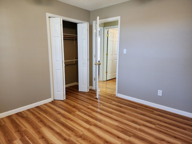 unfurnished bedroom featuring a closet, a textured ceiling, and light hardwood / wood-style flooring